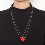 Red heart-shaped acrylic necklace with a silver chain worn as a stylish Valentine's Day jewelry piece.