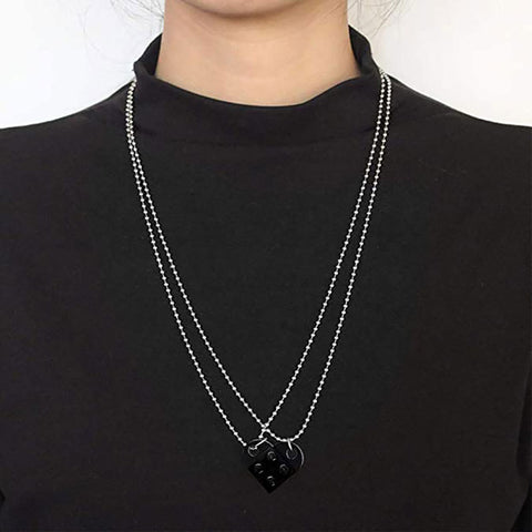 Black heart-shaped acrylic necklace with a silver chain worn as a trendy couple's accessory.