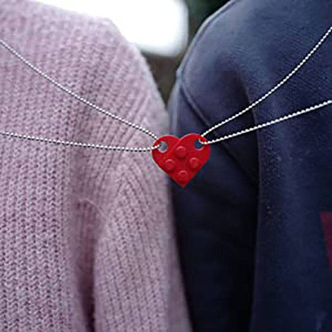 Close-up of a red heart-shaped acrylic necklace worn by a couple, symbolizing love and connection.